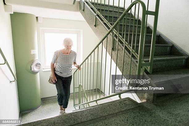 senior woman walking on staircase in apartment building - spostarsi verso lalto foto e immagini stock