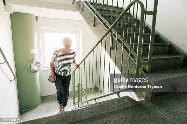 senior woman walking on staircase in apartment building - staircase stock pictures, royalty-free photos & images