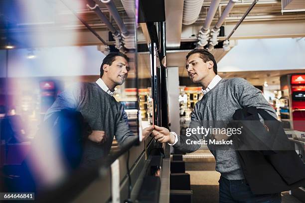 young man shopping for television in electronics store - retailer shopping customer tv stockfoto's en -beelden