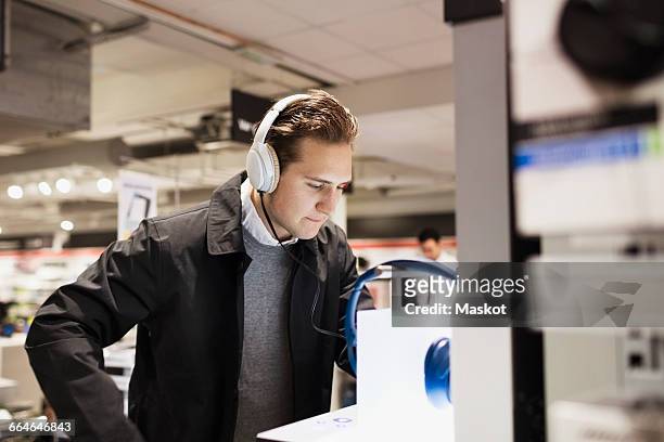 male customer wearing headphones while standing in electronics store - electrical equipment photos et images de collection