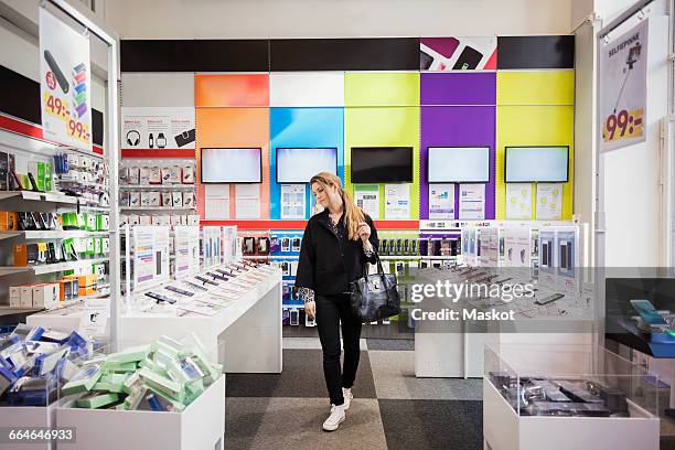 female customer viewing smart phones in store - boodschappentas schoudertas stockfoto's en -beelden