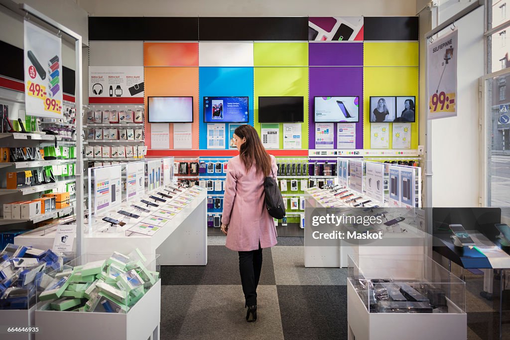 Rear view of female customer viewing smart phones in store