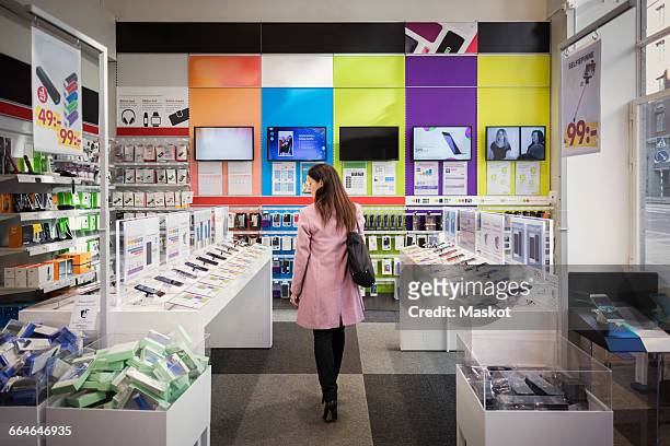 rear view of female customer viewing smart phones in store - consumerism foto e immagini stock