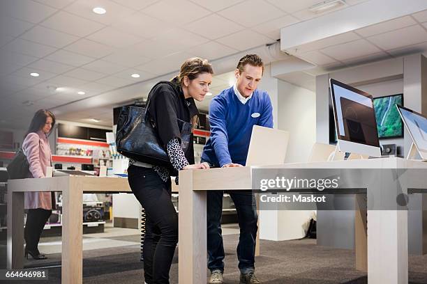 salesman assisting female customer in buying laptop at store - electronic ストックフォトと画像