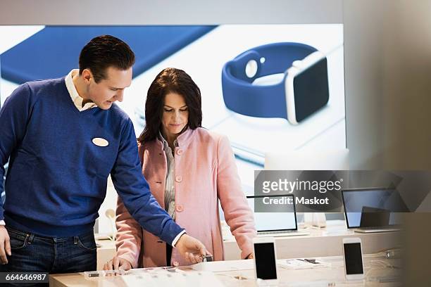salesman assisting customer in buying smart watch at store - consumer electronics industry stock pictures, royalty-free photos & images