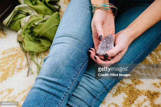 a woman sitting holding a small purple crystal in her hands. - amethyst stock pictures, royalty-free photos & images