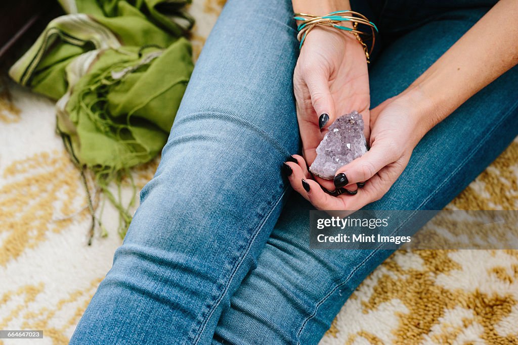 A woman sitting holding a small purple crystal in her hands.