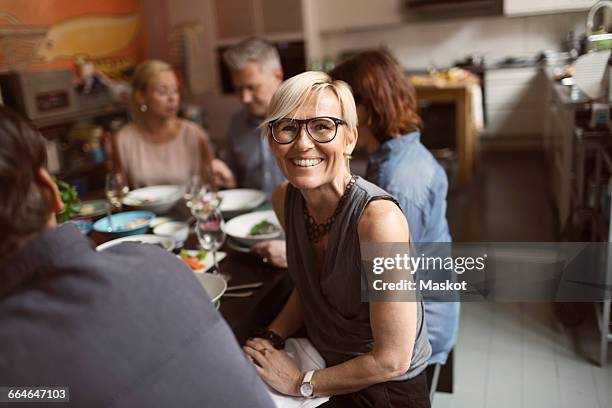 portrait of cheerful mature woman sitting with friends at table - short hair women stock-fotos und bilder