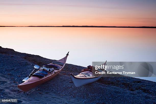 kayaks moored on field by calm lake during sunset - stockholm beach stock pictures, royalty-free photos & images