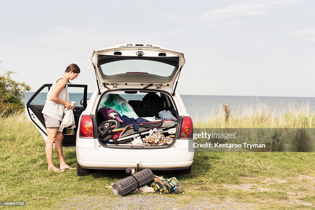 Side view of woman standing by car parked at beach