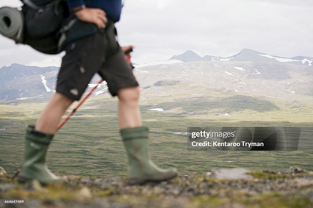 Low section of hiker walking against mountains