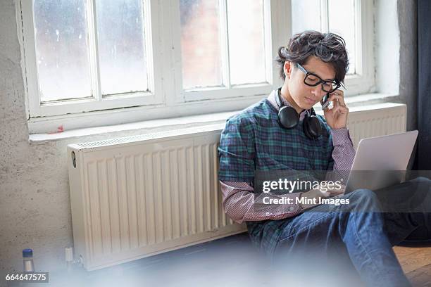 young man sitting on the floor in a rehearsal studio, using a laptop computer. - listening skills stock pictures, royalty-free photos & images
