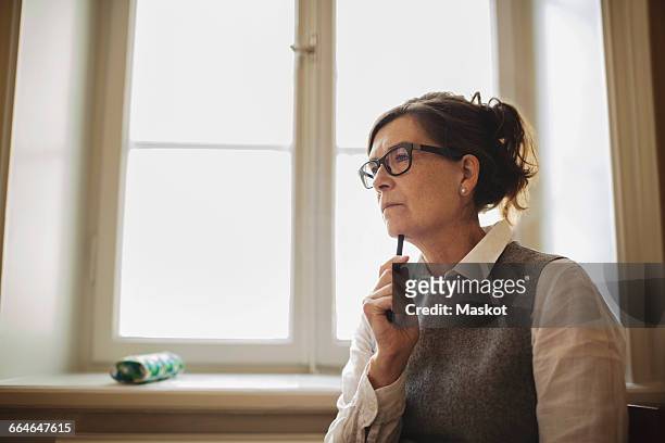 thoughtful female lawyer against window in library - lawyers serious stock pictures, royalty-free photos & images