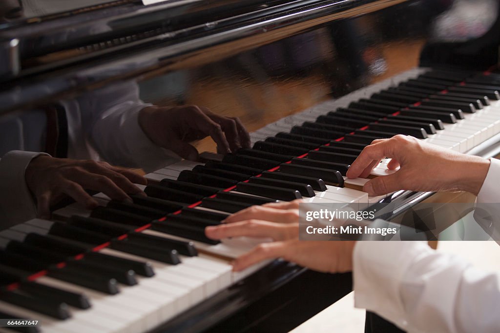 Close up of a pianists hands, playing on a grand piano.