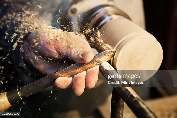 man standing at a woodworking machine in a carpentry workshop, turning a piece of wood. - craft stock-fotos und bilder