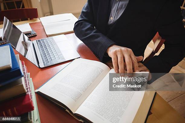 midsection of male professional researching while sitting in law library - studio legale foto e immagini stock