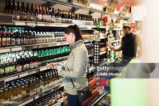 female customer scanning beer bottle in supermarket - buying alcohol stock pictures, royalty-free photos & images