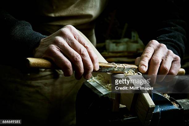 a man working in a furniture makers workshop, using a rasp on a piece of wood in a clamp. - vijl stockfoto's en -beelden