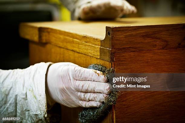 a person in gloves using wire wool to sand down or wax a piece of furniture. - metal sanding stockfoto's en -beelden