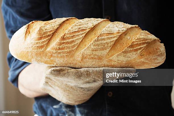 baker holding two freshly baked loaves of bread. - baker smelling bread photos et images de collection