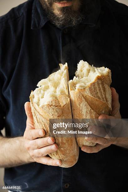 close up of a baker holding two freshly baked loaves of bread. - baker smelling bread stock-fotos und bilder