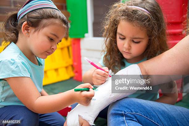 little girls painting her mother's plaster arm - kind gips stock-fotos und bilder