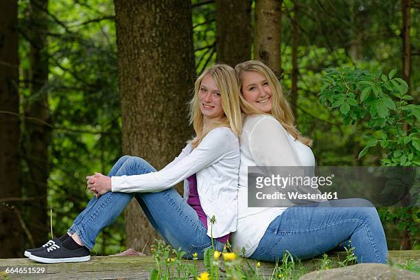 slim and overweight woman sitting back to back at forest edge - slim stock pictures, royalty-free photos & images