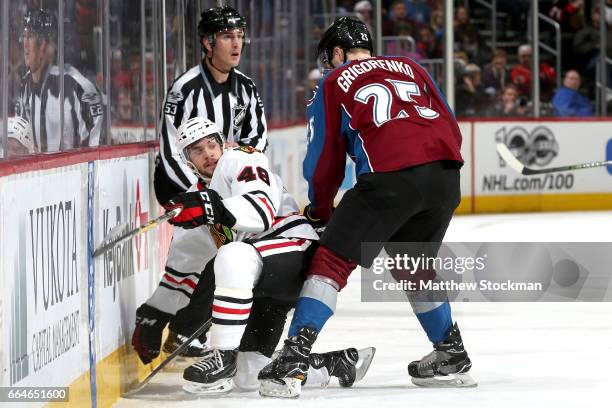 Vinnie Hinostroza of the Chicago Blackhawks battles on the boards against Mikhail Grigorenko of the Colorado Avalanche at the Pepsi Center on April...