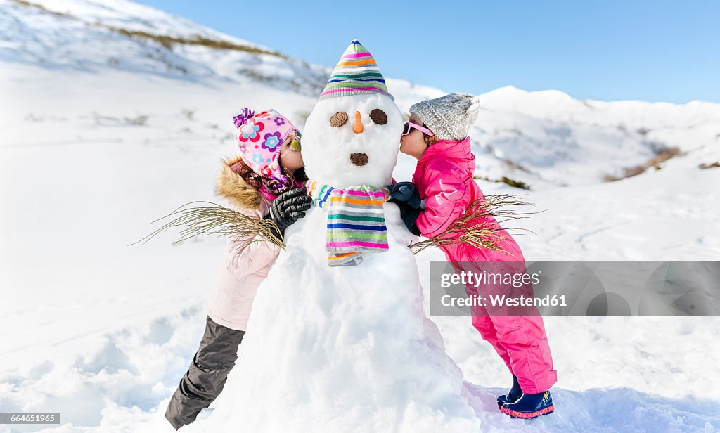 Spain, Asturias, kids playing with snowmen, kissing