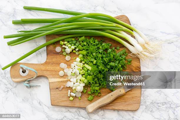 chopped and whole spring onions on wooden board - scallion stock pictures, royalty-free photos & images