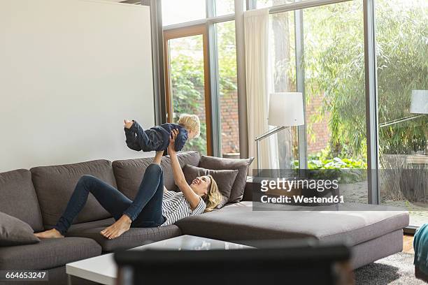 mother and son at home playing on couch - hacer el avión fotografías e imágenes de stock