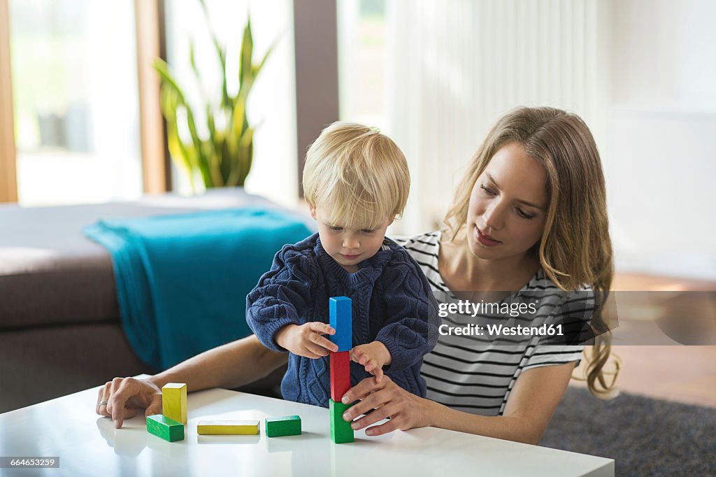 Mother and son stacking building bricks in living room