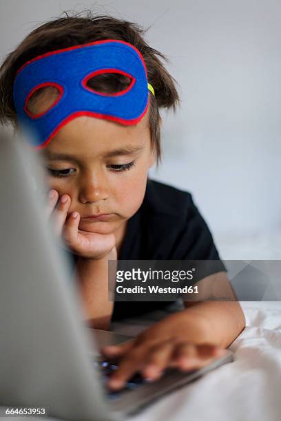 little boy with eye mask lying on bed using laptop - computer wearing eye mask stock pictures, royalty-free photos & images