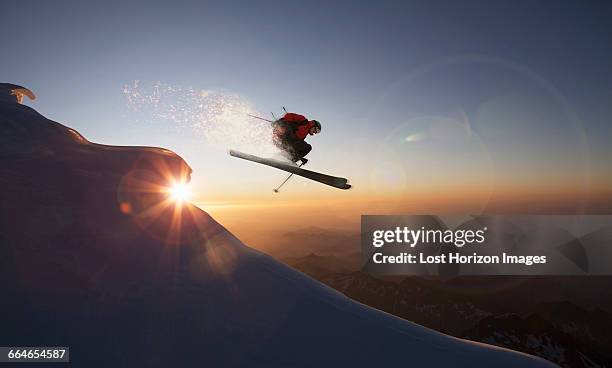 skier jumping on a snowy slope at sunset, zermatt, canton wallis, switzerland - freeze motion stock-fotos und bilder
