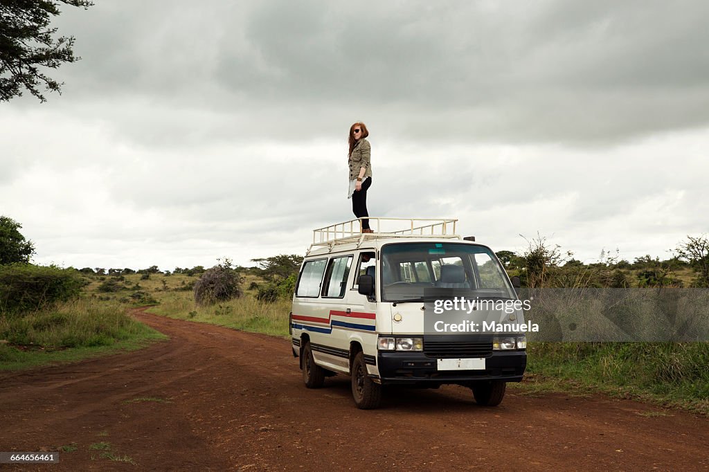 Woman standing on top of vehicle in wildlife park, Nairobi, Kenya