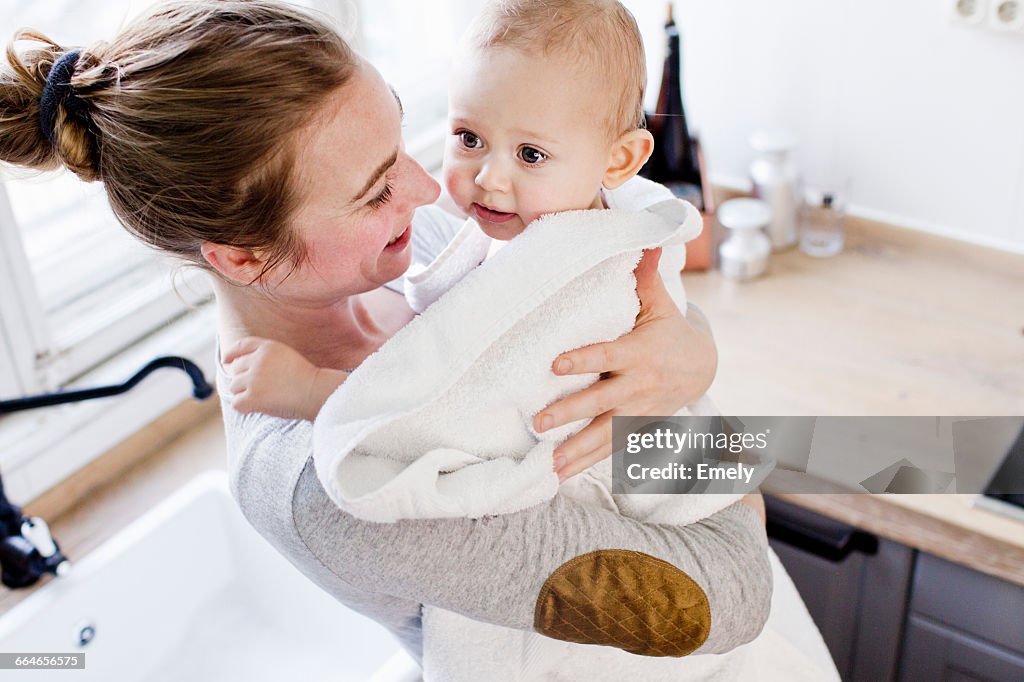 Mother carrying baby son wrapped in towel