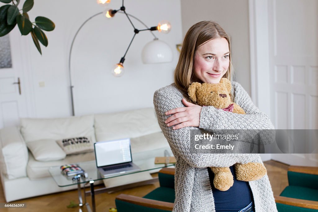Mid adult woman hugging teddy bear in living room