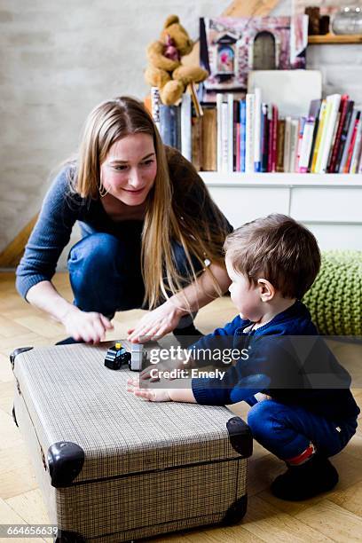 mid adult woman drumming on suitcase with baby son on floor - rhythm stock pictures, royalty-free photos & images
