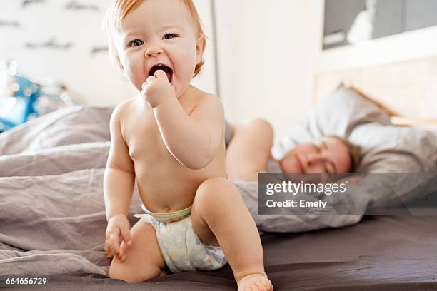 baby girl sitting on bed with tired mother - adult diaper stock pictures, royalty-free photos & images