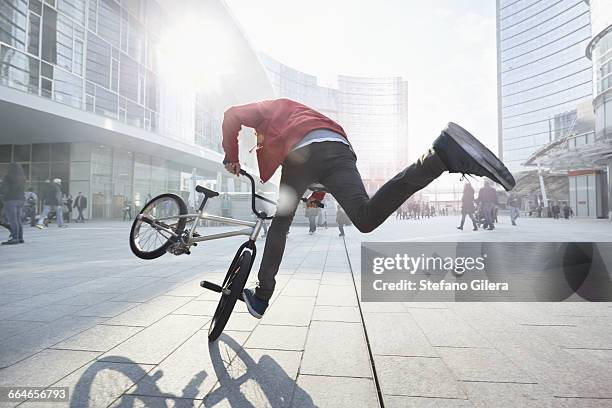 bmx biker doing stunt in urban area - bmx stock-fotos und bilder