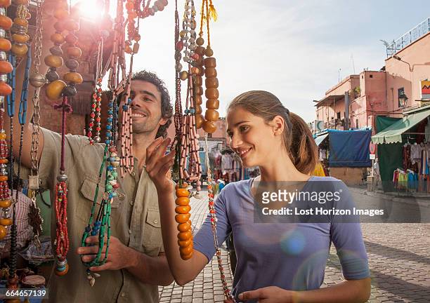 young couple at market looking at beads, jemaa el-fnaa square, marrakesh, morocco - marrakech morocco stock pictures, royalty-free photos & images