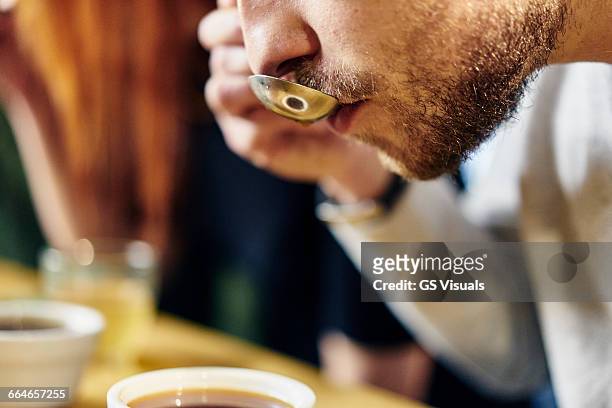 close up of man tasting bowls of coffee at coffee shop tasting - probieren stock-fotos und bilder