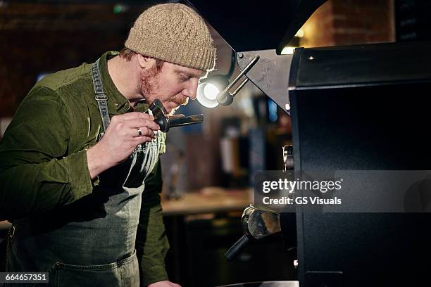 male coffee shop owner at coffee machine smelling coffee - kaffeeröster stock-fotos und bilder