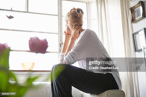 woman sitting in front of window looking out - person in front of house stock pictures, royalty-free photos & images