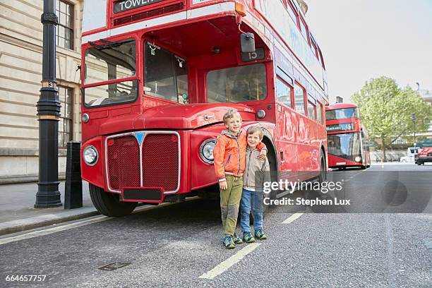 boys in front of red double decker bus - bus front ストックフォトと画像