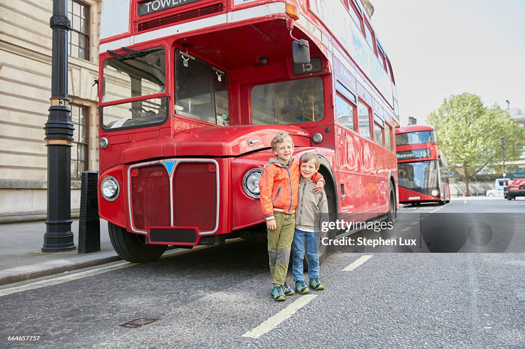 Boys in front of red double decker bus