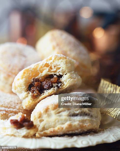 puff pastry minced pies, dusted with icing sugar, on vintage plate, christmas fairy lights in background - christmas mince pies stock-fotos und bilder