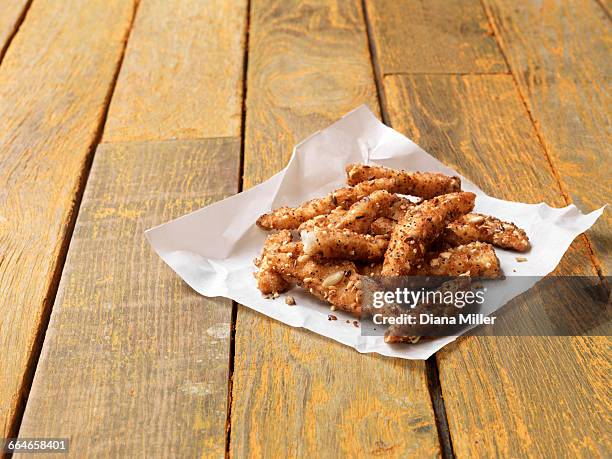 food, fish, super seeded lightly dusted plaice goujons, painted yellow wooden table - wachspapiere stock-fotos und bilder