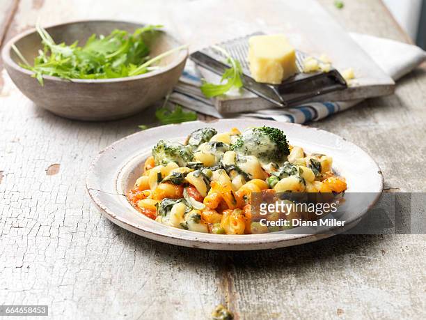 food, vegetarian meals, vegetable pasta bake, melted cheese, onions, peas, broccoli, rocket in bowl, cheese and cheese grater, vintage bowl, rustic wooden table - schaal serviesgoed stockfoto's en -beelden