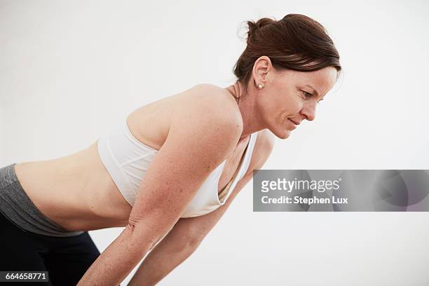 woman in exercise studio wearing crop top bending forward - vornüber beugen stock-fotos und bilder